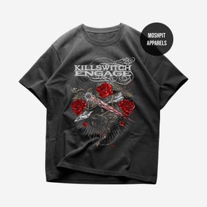May include: Dark gray t-shirt featuring the band name "Killswitch Engage" in white, above a graphic of red roses and a sword. The shirt also has the text "Moshpit Apparels" in a black circle.