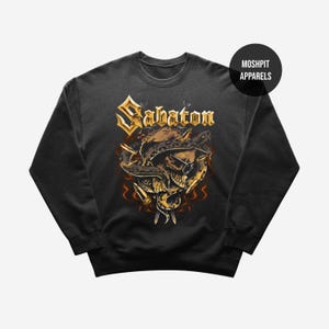 Könnte beinhalten: Dunkelgraues Sweatshirt mit einem Totenkopf-Motiv mit Sonnenbrille, einer Schlange und dem Wort "Sabaton" in Goldbuchstaben. Das Design umfasst Flammen und Messer. Der Markenname "Moshpit Apparels" ist ebenfalls sichtbar.