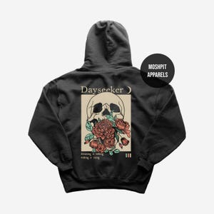 May include: Black hoodie featuring a skull graphic with red and pink flowers. The design includes the text "Dayseeker" and the phrases "dreaming is sinking, waking is rising." A circular logo on the upper right reads "Moshpit Apparels."