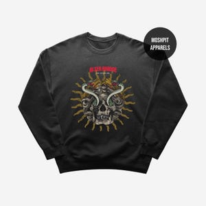 Op de afbeelding: Donkergrijze sweatshirt met een schedelontwerp, slangen, een zonnestraal en de rode tekst "ALTER BRIDGE SIN AFTER SIN". De sweatshirt heeft een ronde hals en lange mouwen. De merknaam "MOSHPIT APPARELS" is ook zichtbaar.