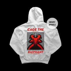 Può includere: Una felpa con cappuccio bianca con un design grafico sul retro. Il design presenta le parole "CAGE THE ELEPHANT" in rosso, con un'immagine astratta rossa e nera al centro. Il marchio "MOSHPIT APPARELS" è in alto a destra.