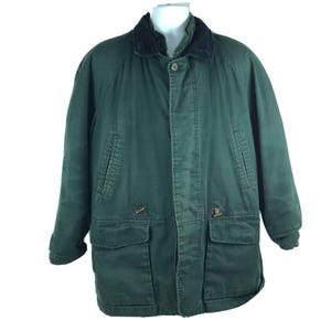 May include: A dark green jacket with a black collar. The jacket has a button closure, two front pockets, and two chest pockets. The jacket is made of a durable material.