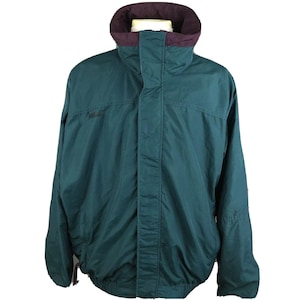 Könnte beinhalten: Dunkelgrüne Jacke mit hohem Kragen und bordeauxfarbenem Innenfutter. Die Jacke hat einen durchgehenden Reißverschluss und einen Kordelzug am Saum. Die Jacke scheint aus wasserabweisendem Material zu sein, das für Outdoor-Aktivitäten geeignet ist.