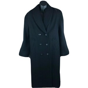 May include: A long, black double-breasted coat with a wide lapel collar. The coat has six dark buttons and two front pockets. The sleeves have a slight bell shape. The coat is displayed on a black mannequin.