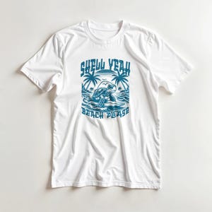 Könnte beinhalten: Weißes T-Shirt mit einem blauen Aufdruck, der eine Schildkröte an einem Strand mit Palmen und den Sätzen "SHELL YEAH" und "BEACH PLEASE" zeigt. Das Design ist mittig auf der Vorderseite des Shirts platziert.