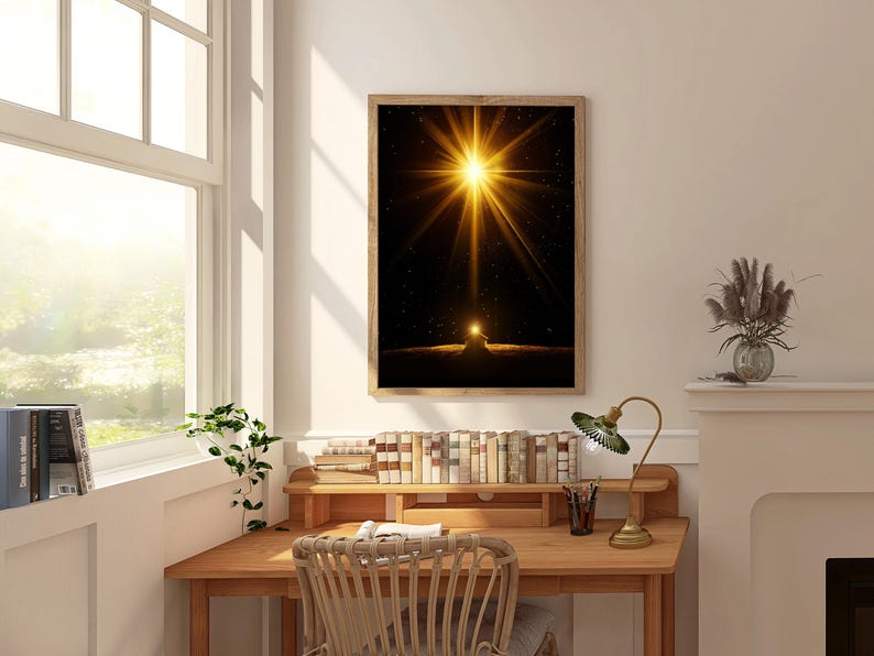 May include: A framed art print featuring a bright golden light emanating from a dark background. The artwork is displayed above a wooden desk with books, a lamp, and a woven chair. The room has a window with natural light.