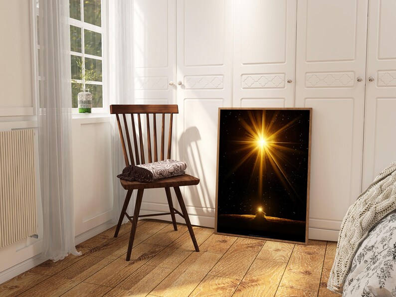 May include: A framed art print featuring a bright golden starburst against a black background. The artwork is displayed in a room with a wooden chair and a window with natural light.