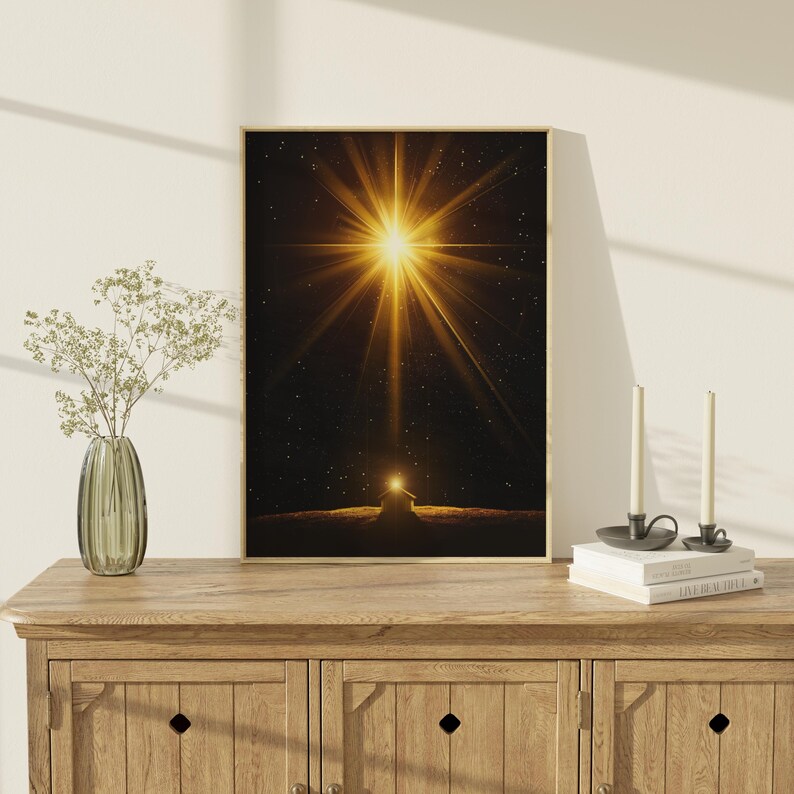 May include: Framed art print featuring a bright golden starburst over a dark landscape with a small building. The artwork is displayed on a wooden cabinet with a vase of flowers and candles.