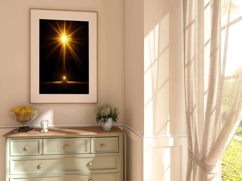 May include: A framed art print featuring a bright, golden starburst against a dark background. The artwork is displayed above a light green dresser with wooden knobs. A glass bowl of lemons and a small plant in a white pot are also visible.