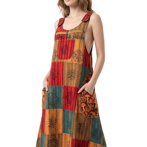 May include: A sleeveless midi-length pinafore dress featuring a patchwork design with vertical stripes in shades of red, orange, yellow, and teal. The fabric is decorated with black printed sun motifs and a mushroom pattern on the front pockets.