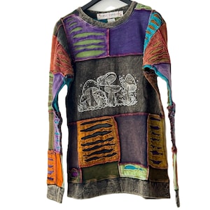 May include: A long-sleeved patchwork sweatshirt with a crew neck. The shirt features a variety of colors, including purple, orange, green, and brown. A white illustration of mushrooms is on the front. The brand name "Funky Threads" is on the collar.