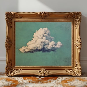 Puede incluir: Impresión artística enmarcada que muestra una nube blanca sobre un fondo turquesa. El marco dorado ornamentado añade un toque clásico. La obra de arte está colocada sobre una alfombra estampada, creando un contraste.