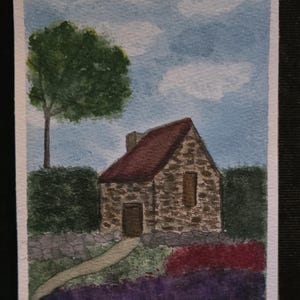 May include: Watercolour painting of a stone cottage with a red tiled roof, set against a blue sky with clouds. A green tree and hedge frame the cottage, with a path leading to the door. The painting is signed "KN".