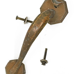 May include: A vintage, octagonal-shaped door handle with a curved lever, made of metal with a worn, brown finish. Two screws and washers are included.