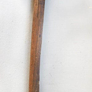 May include: A vintage wooden-handled hammer with a black metal head. The hammer has a slightly curved handle and a worn, weathered look.