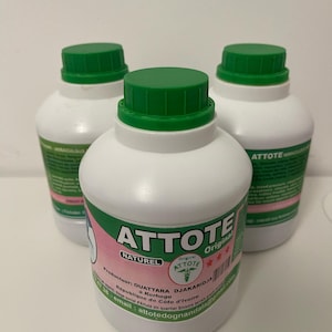 May include: Three white plastic bottles with green caps. Each bottle has a label with the word "ATTOTE" in large letters, along with other text and a pink and green design. The bottles are arranged in a group.