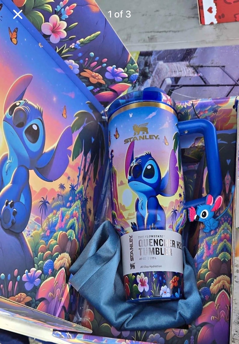 May include: A blue Stanley Flowstate Quencher H2.0 Tumbler with a Stitch design, featuring a blue handle and a small Stitch figure. The tumbler is in a box with a matching Stitch design. The box has the text "1 of 3".