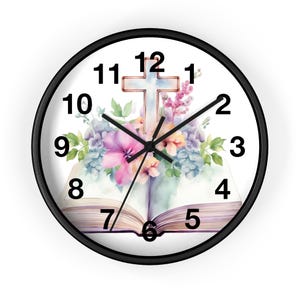 May include: Circular wall clock with a black surround and a white face. The clock face features a watercolour design of a cross, flowers, and an open book. Black hands show the time. Numbers 1 to 12 are displayed.