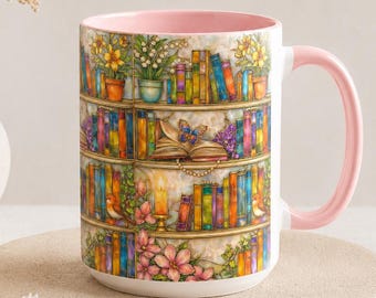 May include: A ceramic mug with a light pink interior and handle, featuring a colourful wrap-around illustration of wooden bookshelves filled with various books, potted plants, a butterfly resting on an open book, and pink floral accents.