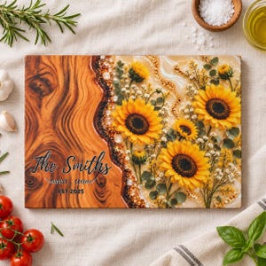 May include: A rectangular wooden serving board featuring a natural wood grain on the left and a resin-filled section on the right containing embedded sunflowers and greenery. The text reads The Smiths EST 2025 in black script and print.