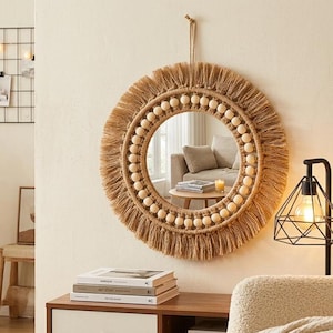 Può includere: Specchio da parete rotondo con un design bohémien naturale. Lo specchio presenta una cornice in iuta intrecciata con un bordo a frange e perline di legno. È appeso a una corda di iuta, aggiungendo un tocco rustico.