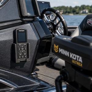 May include: A black and gray boat console with a mounted control panel and a Minn Kota Ultrex trolling motor. The boat interior includes a steering wheel, a Skeeter seat, and a view of the water.