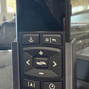 May include: Black Minn Kota trolling motor remote control with multiple function buttons, including anchor, speed, and directional controls. The remote is held in a black 3D-printed cradle.