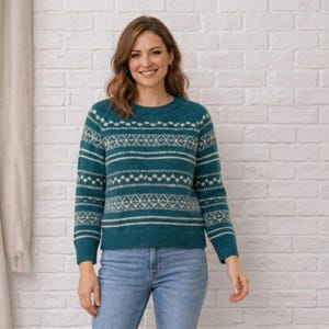 Puede incluir: Un suéter de manga larga color verde azulado con un patrón geométrico blanco de estilo Fair Isle en el pecho, las mangas y la espalda. La prenda de punto tiene cuello redondo, puños y dobladillo acanalados, combinada con jeans azul claro.