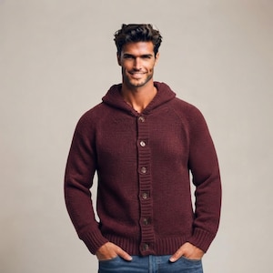 May include: A dark burgundy knit cardigan featuring a hood, long sleeves with ribbed cuffs, and a front button-down closure with five visible buttons. The garment is constructed from a textured knit fabric and is worn over blue denim jeans.
