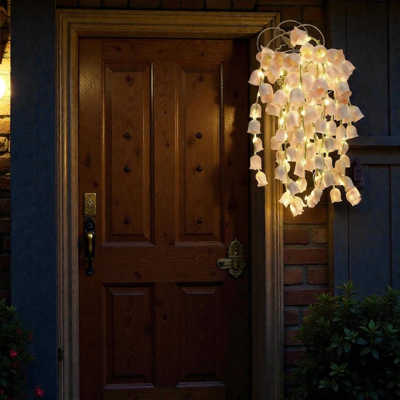 May include: A decorative hanging light fixture with cascading, petal-shaped lights. The lights are a soft white color and are arranged in a cluster, creating a warm and inviting ambiance. The fixture is mounted on a wooden door.