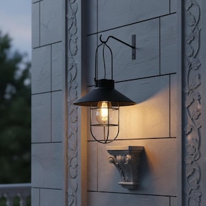 May include: Black outdoor wall-mounted light fixture with a cage-like design. The light has a black shade and a clear glass bulb. The fixture is mounted on a light gray stone wall with decorative molding.