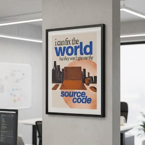 May include: A framed poster with the text "I can fix the world but they won't give me the source code." The poster features a cityscape, a laptop graphic, and orange and blue text. The poster is hanging on a white wall.