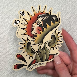 Puede incluir: Una pegatina con un diseño de tatuaje vintage. Muestra el perfil de una mujer con un sol, abejas y elementos florales en rojo, amarillo y verde. La pegatina tiene un fondo beige y el texto "@APPLEBARNART".