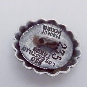 May include: Silver button with a scalloped edge. The button has the text "MADE IN MEXICO" and "LOS CASTILLO" with the number "23" and "980" printed on it.