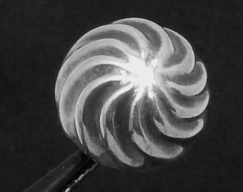 Könnte beinhalten: Nahaufnahme eines silbernen, spiralförmigen Dekorationsobjekts. Das Objekt ist glatt und glänzend, mit einem Spiralmuster.