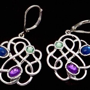 May include: Silver Celtic knot earrings with blue, green, and purple gemstones.