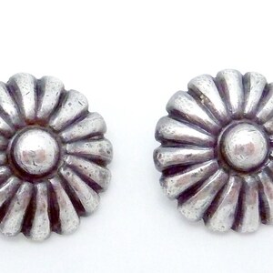 May include: A pair of silver flower-shaped earrings with a raised center.