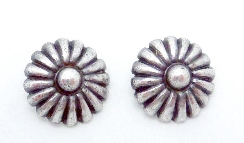 May include: A pair of silver flower-shaped earrings with a raised center.