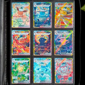 Puede incluir: Nueve cartas coleccionables de Pokémon en una carpeta. Las cartas presentan varios personajes Pokémon, incluyendo Eevee, Vaporeon, Jolteon, Umbreon, Espeon, Glaceon y Sylveon. Cada carta tiene un diseño único con colores vibrantes y detalles.
