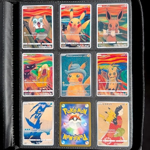 May include: A collection of nine Pokémon trading cards in a binder. The cards feature various Pokémon characters in artistic renditions, including Pikachu and Eevee. The cards are in a black binder.