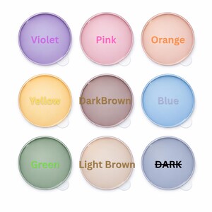 May include: Nine circular designs in various colours, each labelled with a colour name. The colours are violet, pink, orange, yellow, dark brown, blue, green, light brown, and dark.