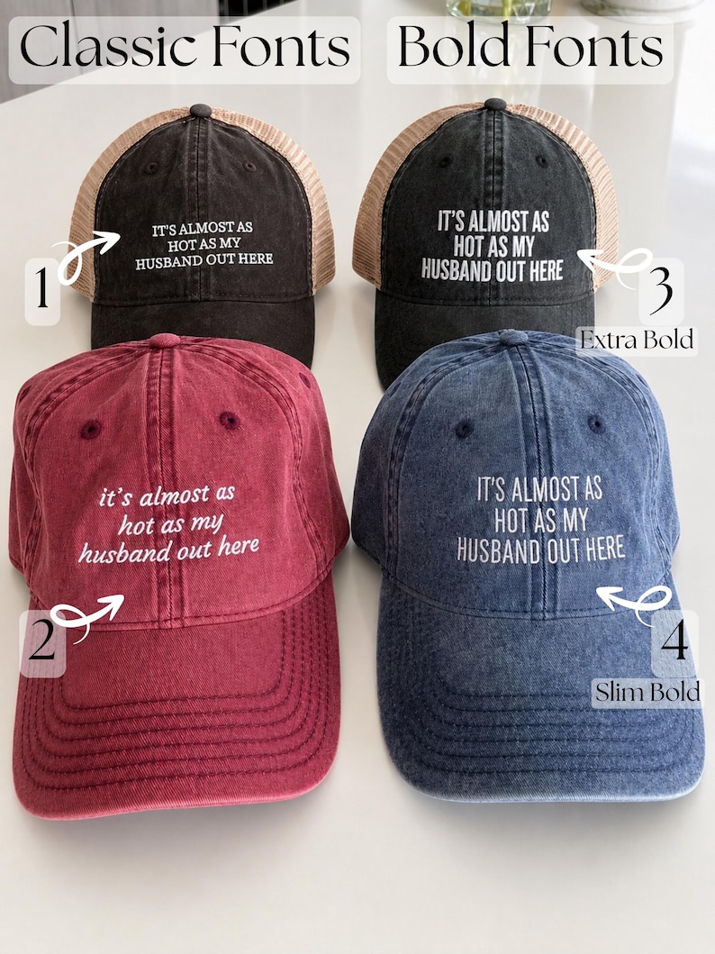 May include: Four trucker hats in black, red, and blue with mesh backs. Each hat features the white embroidered text 'IT'S ALMOST AS HOT AS MY HUSBAND OUT HERE' in varying font styles labeled 1 through 4, categorized as Classic Fonts and Bold Fonts.