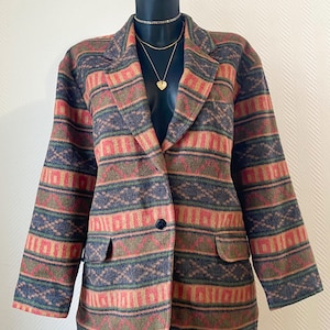 Peut inclure: Un blazer à motifs dans les tons de rouge, vert et bleu, présenté sur un mannequin. Le blazer présente un motif géométrique, une fermeture à un seul bouton et deux poches avant. Le blazer a un revers classique et des manches longues.