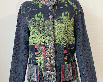 May include: A patchwork jacket with a high collar and button closure. The jacket features a mix of patterns, including floral and geometric designs in shades of green, black, and red. The sleeves are a dark gray, open-knit style.