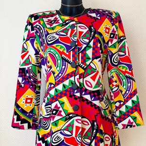 Peut inclure: Un blazer à motifs vibrants avec un design géométrique audacieux en rouge, jaune, vert, violet et blanc. Le blazer est orné de boutons noirs et d'un col classique. Les manches trois-quarts et la coupe ajustée créent un look vintage élégant.