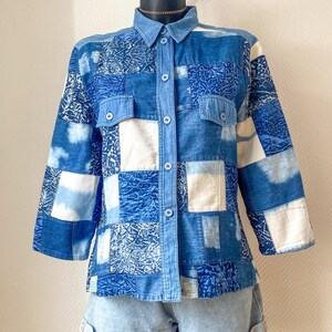 Könnte beinhalten: Ein Patchwork-Jeanshemd mit Kragen, zwei Brusttaschen und Knopfverschlüssen. Das Hemd hat eine Mischung aus blauen und weißen Jeans-Patches. Kombiniert mit hellblauen Jeansshorts.