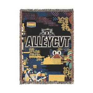 May include: A woven throw blanket featuring a black background with a large white text graphic reading ALLEYCVT. The design includes a cartoon cat head, a small ZOOMIES label, and colourful pixelated patterns in yellow, blue, and red with fringed edges.