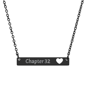 May include: A black necklace with a bar pendant. The pendant has the text "Chapter 32" and a heart-shaped cutout. The necklace chain is also black.