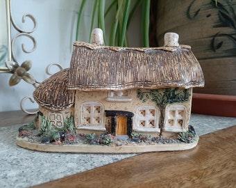 Pequeña cabaña de cerámica con techo de paja