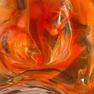 May include: Abstract artwork featuring swirling patterns of orange, red, brown, and white. The colors blend and flow, creating a dynamic and textured visual effect. The artwork evokes a sense of movement and depth.